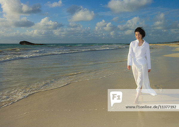 Japanische Frau geht am Strand spazieren
