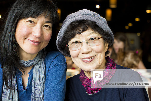 Older Japanese mother and daughter smiling in restaurant