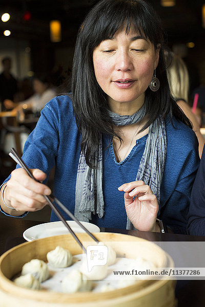 Japanerin isst Essen mit Stäbchen