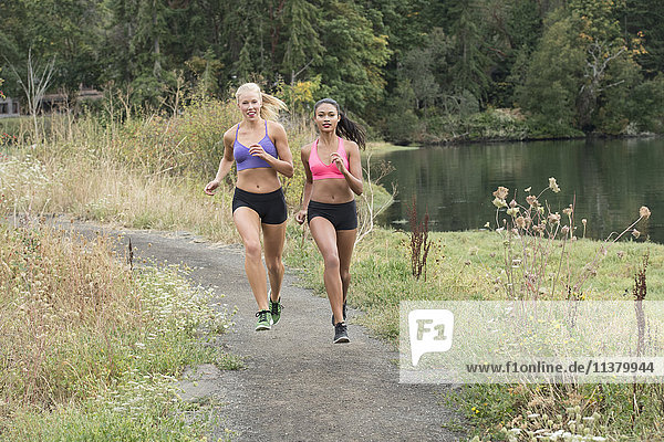 Women running on park path near lake