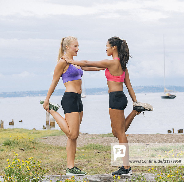 Women stretching legs near lake