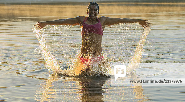Gemischtrassige Frau plantscht im See