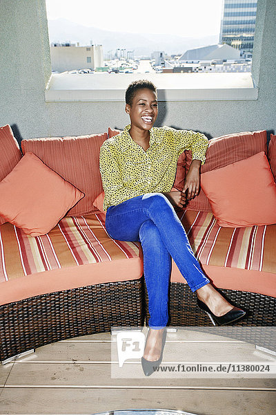 Black woman sitting on rooftop sofa