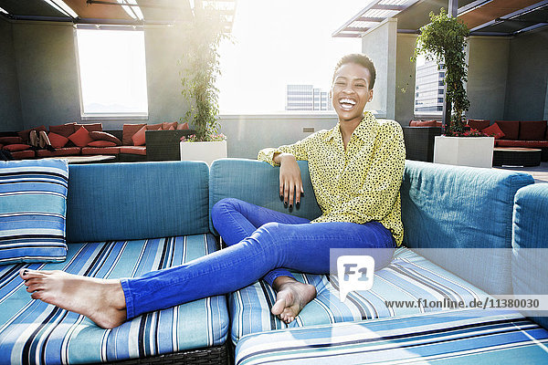 Black woman laughing on rooftop sofa
