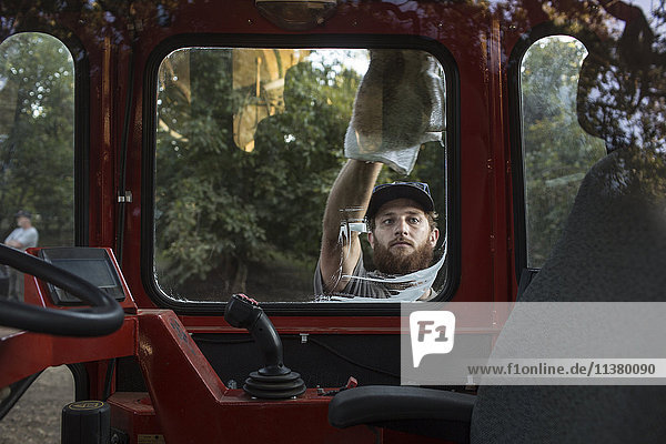 Caucasian man washing window of tractor
