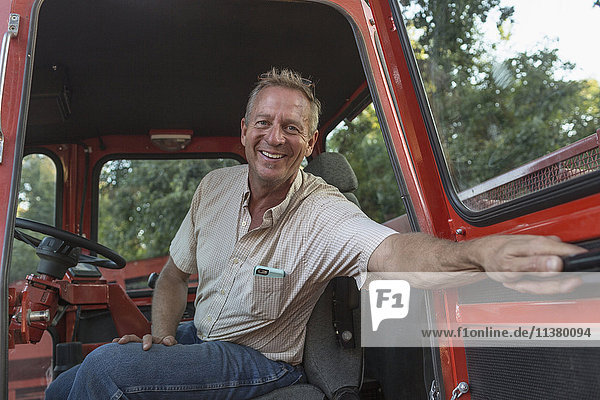 Smiling Caucasian man holding door of tractor