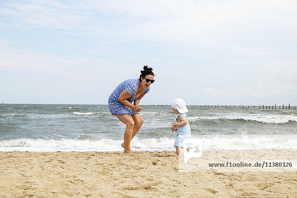 Caucasian mother and baby son playing at beach