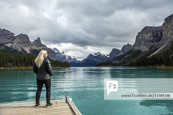 Caucasian woman standing at the end of dock on mountain lake