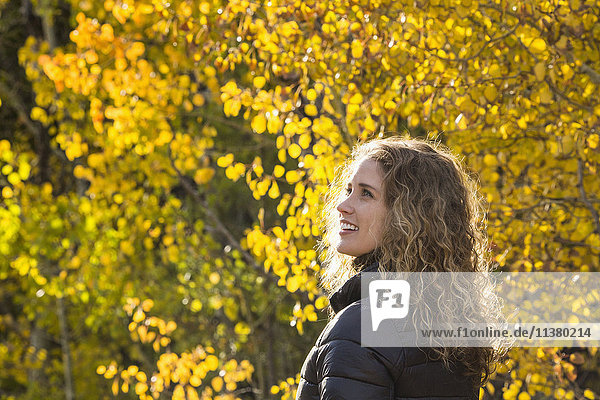 Smiling Caucasian woman under autumn leaves