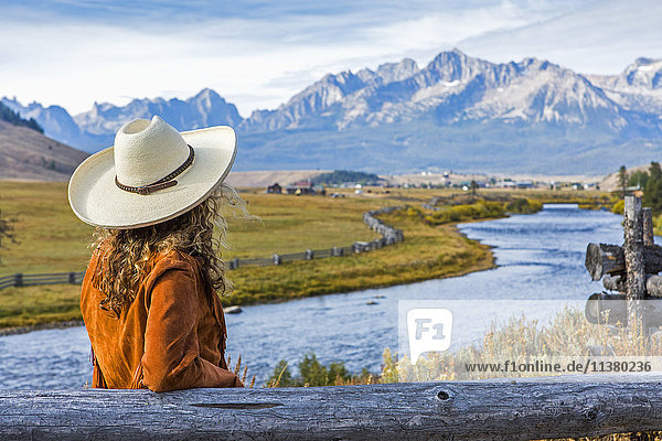 Caucasian woman leaning on wooden fence near mountain river