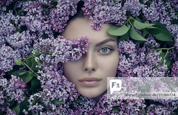 Gesicht einer kaukasischen Frau  umgeben von lila Blumen