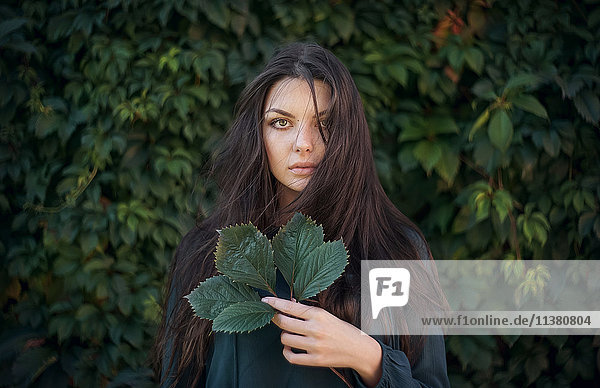 Kaukasische Frau hält Blätter