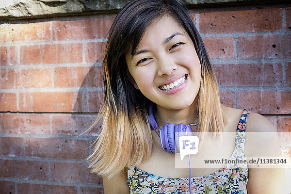 Porträt einer lächelnden chinesischen Frau mit Kopfhörern