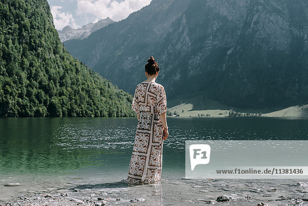Kaukasische Frau watet in einem Bergsee