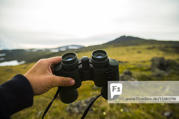 Hand of man holding binoculars outdoors