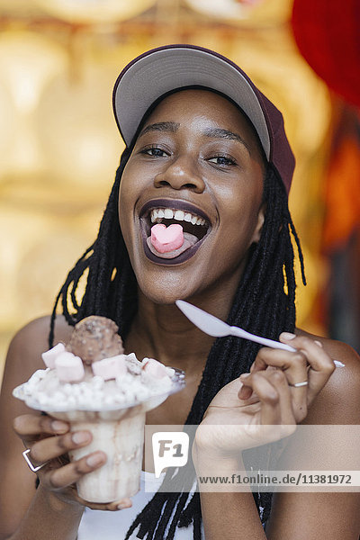 Mixed-Race-Frau zeigt herzförmige Bonbons auf der Zunge
