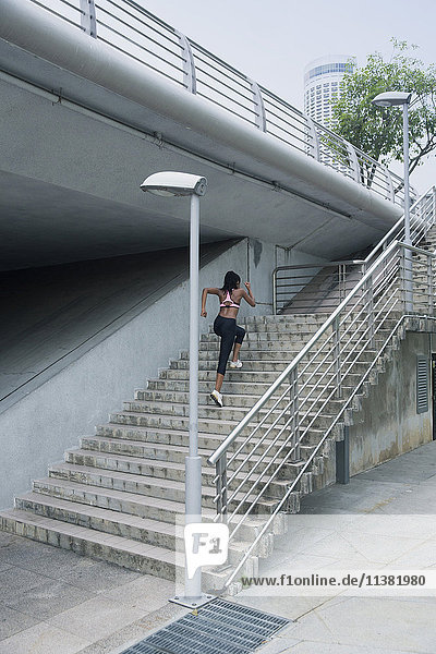 Gemischtrassige Frau läuft eine städtische Treppe hinauf
