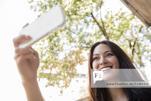 Smiling Thai woman posing for cell phone selfie