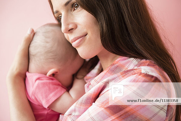 Caucasian mother hugging baby daughter