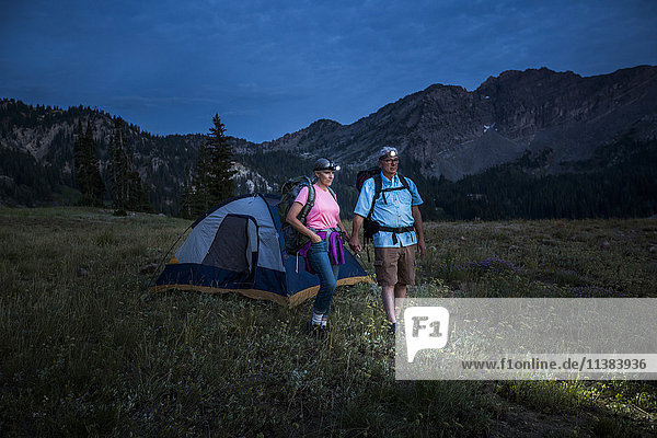 Kaukasisches Paar mit Stirnlampen auf einem Bergcampingplatz