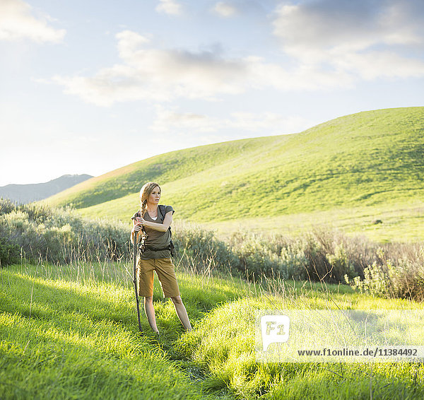 Kaukasische Frau mit Spazierstock auf einem Hügel