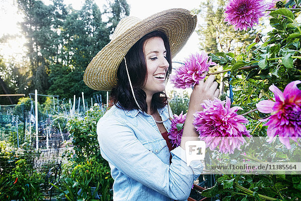 Caucasian woman smelling flower in garden
