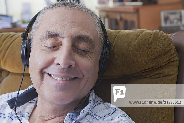 Lächelnder hispanischer Mann  der Kopfhörer hört