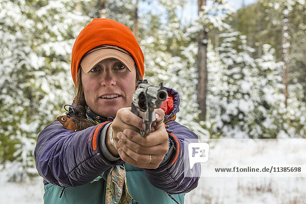 Kaukasische Frau  die im Winter mit einer Handfeuerwaffe zielt