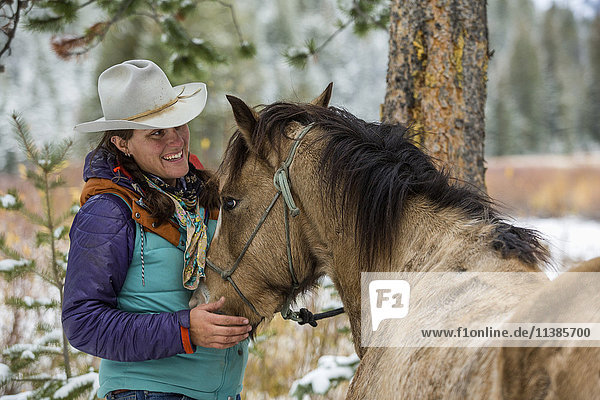 Kaukasische Frau streichelt Pferd im Winter