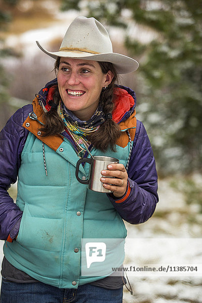 Lächelnde kaukasische Frau hält Metallbecher im Winter
