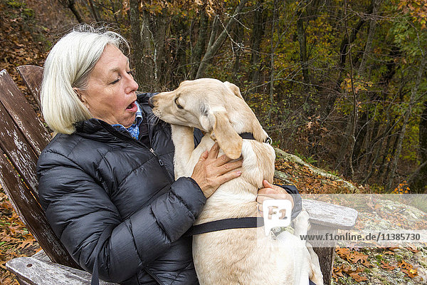 Kaukasische Frau hält Hund im Schoß im Freien
