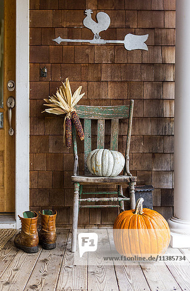 Kürbisse und Mais auf der Veranda mit Stiefeln im Herbst