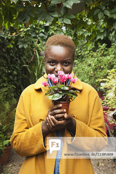 Porträt einer lächelnden schwarzen Frau  die an Blumen riecht