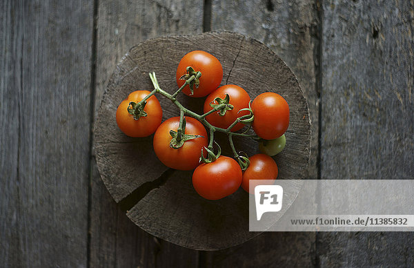 Tomaten an einer Rebe auf einer hölzernen Baumscheibe