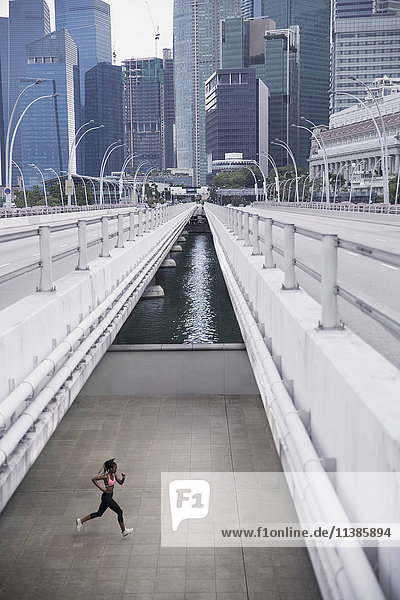 Gemischtrassige Frau läuft unter städtischer Brücke