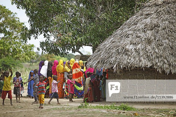 Frauen und Kinder in farbenfroher Kleidung neben einer Lehmhütte  ethnische Gemeinschaft der Orma  Marafa  Tana River Delta  Kenia  Afrika