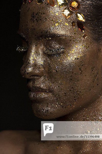 Side portrait  young woman with golden glitter makeup
