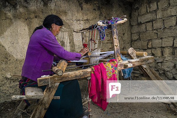 Einheimische Frau beim Weben von Stoffen auf einem Webstuhl  im Freien  Jhong  Bezirk Mustang  Nepal  Asien