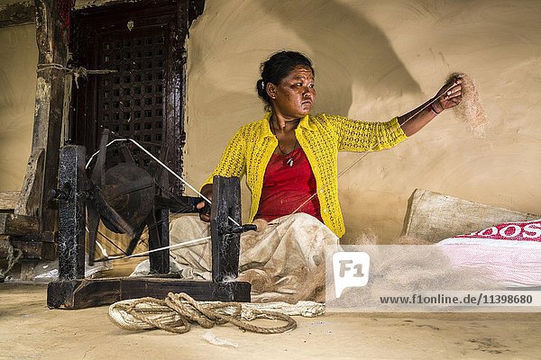 Einheimische Frau beim Spinnen von Schafwolle mit traditionellem Spinnrad vor dem Haus  Ghandruk  Bezirk Kaski  Nepal  Asien