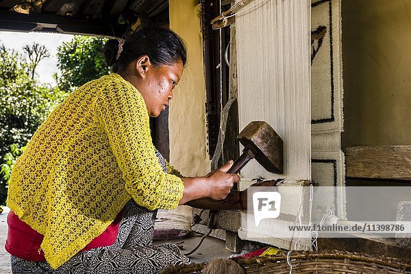 Einheimische Frau knüpft einen Teppich aus Schafwolle vor ihrem Haus  Ghandruk  Bezirk Kaski  Nepal  Asien