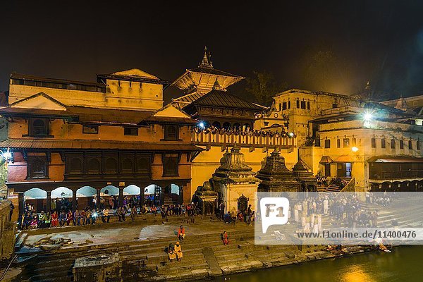 Pashupatinath temple with people at gaths  banks of Bagmati River  illuminated at night  Kathmandu  Kathmandu District  Nepal  Asia