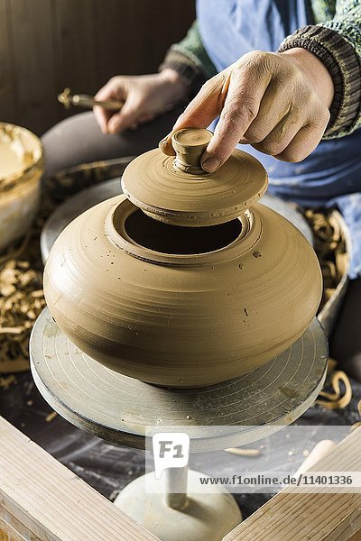 Keramikwerkstatt  Hand hält den Deckel einer Dose über der Töpferscheibe  Pittenhart  Oberbayern  Deutschland  Europa