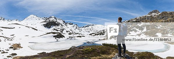 Young man  hiker looking at frozen lake  Unterer Giglachsee  mountain landscape with residual snow  Rohrmoos-Obertal  Schladming Tauern  Schladming  Styria  Austria  Europe