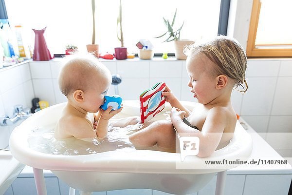 Small children  siblings sitting together in a bathtub  Germany  Europe
