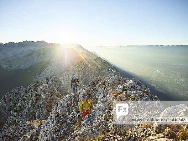 Sunrise on ridge  via ferrata  two climbers attached to steel cable  Nordkette Innsbruck  Tyrol  Austria  Europe