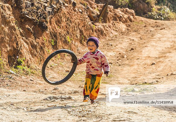 Little boy runs with tire as toy  Palaung hilltribe  Palaung Village in Kyaukme  Shan State  Myanmar  Asia
