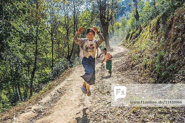 Junge springt fröhlich auf unbefestigter Straße  Palaung Bergvolk  Palaung Dorf in Kyaukme  Shan Staat  Myanmar  Asien
