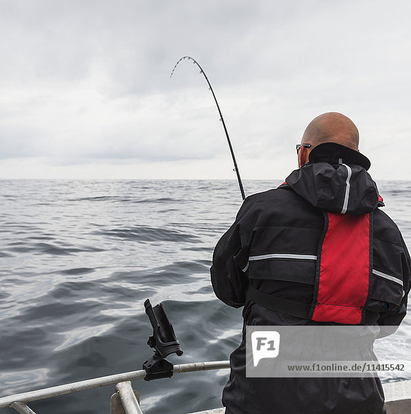 Ein Mann fischt von einem Fischerboot aus vor den Queen Charlotte Islands; British Columbia  Kanada'.