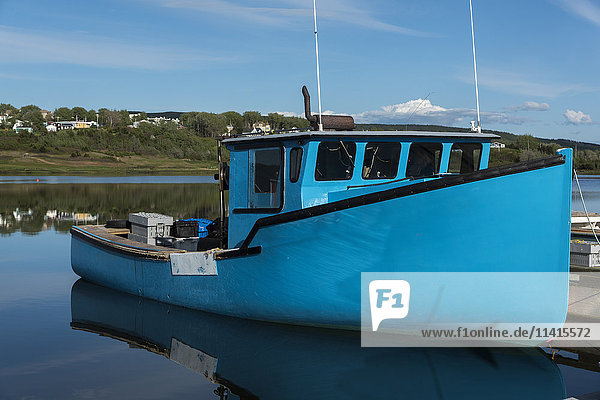 'Blue boat moored against a dock in Inverness Harbour; Mabou  Nova Scotia  Canada'