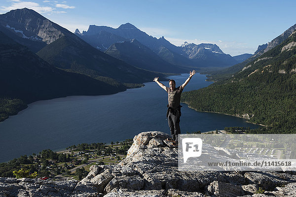 Ein Mann steht auf einem felsigen Bergrücken mit Blick auf einen See und Berge im Waterton Lakes National Park; Alberta  Kanada'.